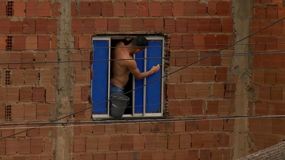 Morador tenta vedar janela no segundo andar de uma casa para evitar que água da chuva entre na residência - Foto: Reprodução/TV Gazeta